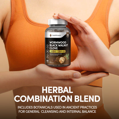 Hands holding HealthEssent Wormwood Black Walnut Clove supplement bottle - traditional herbal formula with added pumpkin seed and papaya seed for complete digestive support